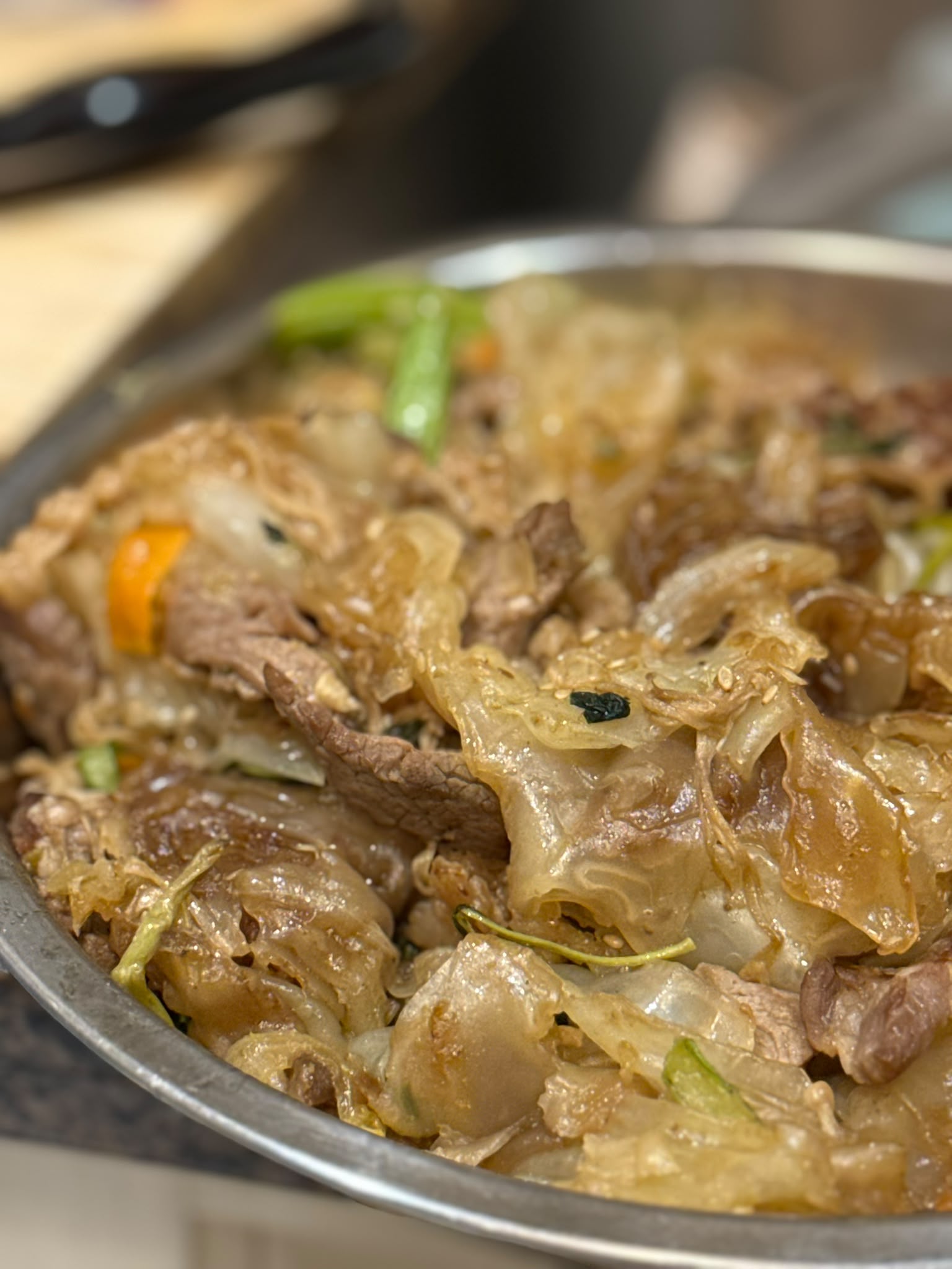 Silky sheets folded through beef, greens, onion, and carrot.