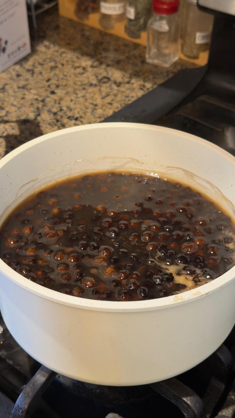 The pearls simmering in deep brown sugar syrup — let them soak so they sweeten through and stay soft and chewy.
